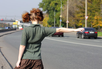 Girl is hitch-hiking on road