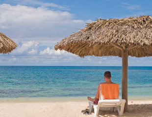 Man reading and relaxing on a secluded beach.