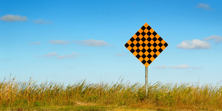 Dead end sign against a blue sky, with grass.