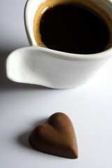 Cup of espresso coffee with heart shaped chocolate candy