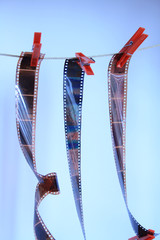 Films hanging with rope and clothespins on blue background