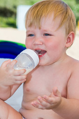 Portrait of the laughing child with a bottle of milk