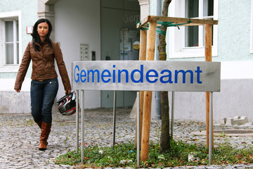 Junge Frau vor Gemeindeamt mit Sturzhelm