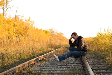 A man sitting on the railroad tracks, in a deep depression