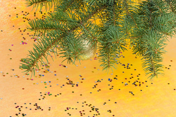 Fir tree branch with decoration on a yellow background.