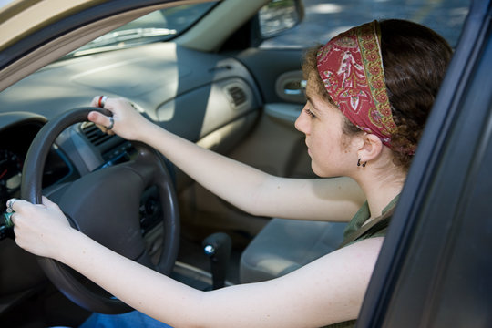 Teen girl concentrates on learning to drive.