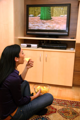 Ungesunde Ernährung einer Frau vor Fernsehapparat