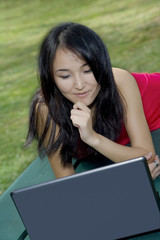 Beautiful Asain student studing using a computer at a park