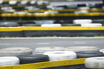 Old tyres used as bumper zone at a go-kart race circuit. - obrazy, fototapety, plakaty