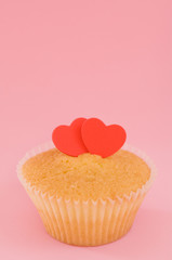 Cupcake with red hearts over a pink background