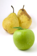 Green apple with leaf in front of two pears