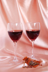 Two glasses of red wine with necklace and ear-ring