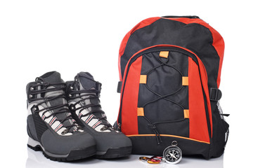 Hiking boots, compass, and backpack over a white background