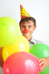 Fototapeta na wymiar Young boy with party horn and clown noses holding balloons