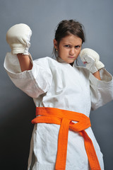 Little girl in martial arts unifor doing karate