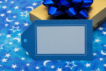 Gold present with blue bow and blank gift tag on moon and star