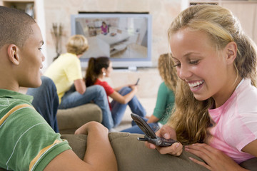 Teenagers Hanging Out In Front Of Television Using Mobile Phones