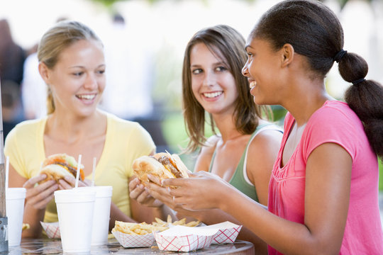 Teenage Girls Sitting Outdoors Eating Fast Food