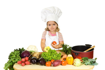 Little girl with a chefs hat, apron and lots of vegetables