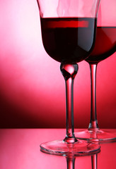 Two glasses of red wine over red background..