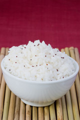 white bowl of boil chinese rice over bamboo