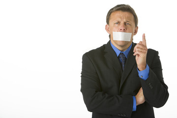 Businessman With His Mouth Taped Shut And Pointing