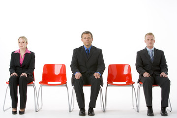 Three Business People Sitting On Red Plastic Seats