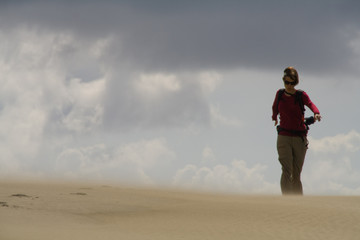 A lonely girl walking over a sand dune