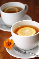 Hot teacups with lemon and flowers.