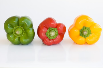 Red green and yellow pepper on white background