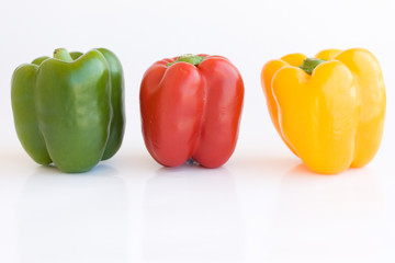 Red green and yellow pepper on white background