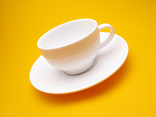 white cup and plate on  yellow background,  close up