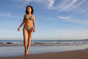 Beautiful slim girl walking on beach