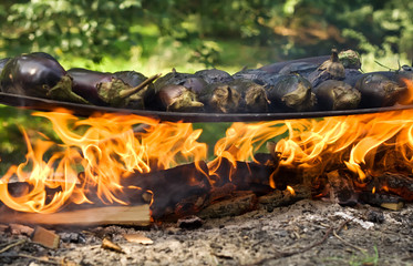 Eggplants cooking on a metal plate over open fire