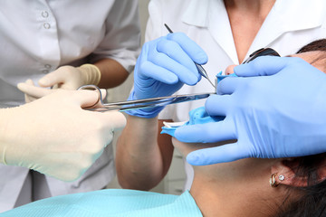 close up with hands in blue gloves and dental tools