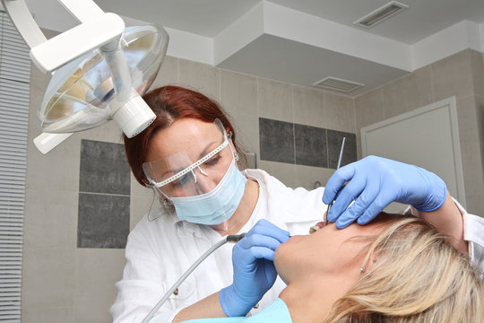 Female Dentist Is Drilling The Patients Tooth