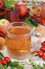 Cup of rose hip tea with fresh briars and autumn decoration