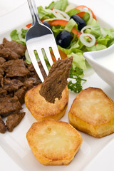 Grilled meat with baked potatoes, sauce and vegetable salad