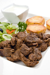 Grilled meat with baked potatoes, sauce and vegetable salad