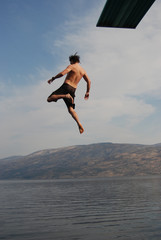 Man jumping from a jumping board into okanagan lake.