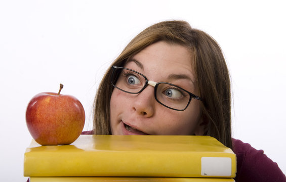 Close-up view of nerdy female student looking at apple.
