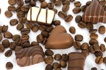 Coffee beans and chocolate candies on white background