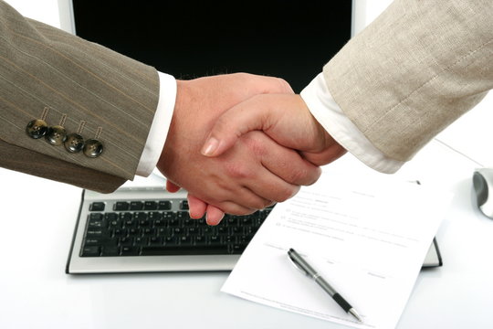 man and woman shaking hands in front of computer and document