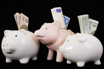 Piggybank with various currencies on black background.