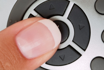 Close-up of a finger pressing the button on the remote control