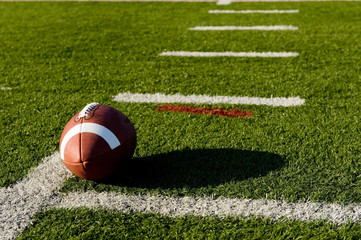 A brown leather American football on a green football field