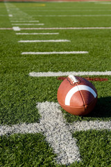 A brown leather American football on a green football field