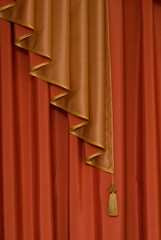 red window shade with a decoration as a gold brush