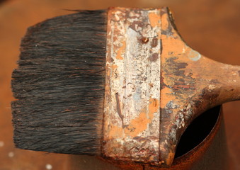 Old and very worn paint brush on a rusty tin
