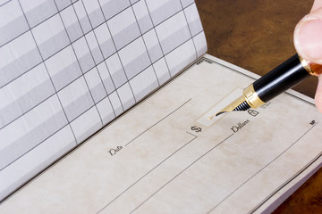 Hand holding pen writing in chequebook , paying the bills